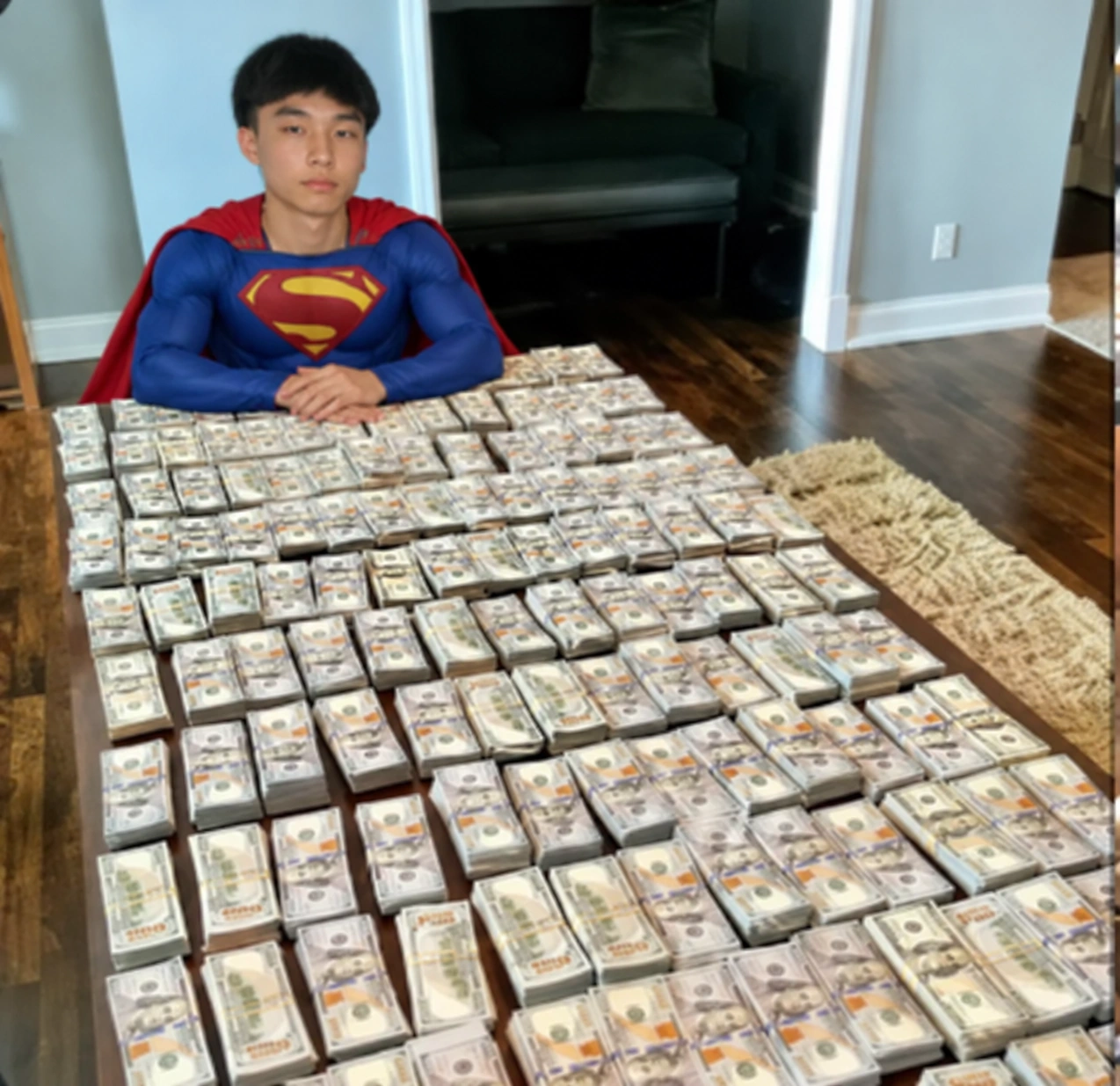 Super Kimchi in a Superman costume sitting at a table covered in money